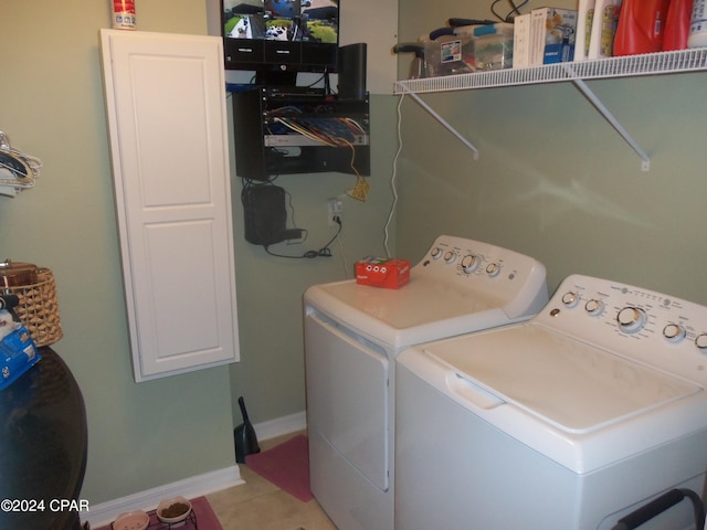 clothes washing area with washing machine and clothes dryer, cabinets, and light tile patterned floors