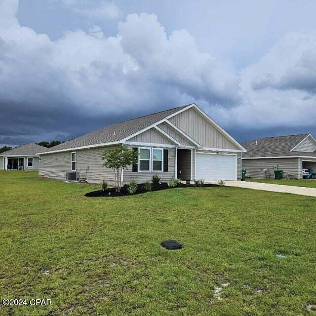 view of front of house featuring central AC, a front lawn, and a garage