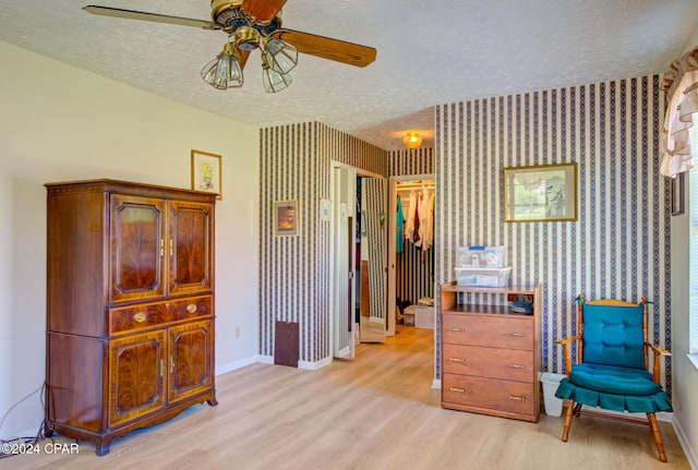 sitting room with ceiling fan, a textured ceiling, and light hardwood / wood-style flooring