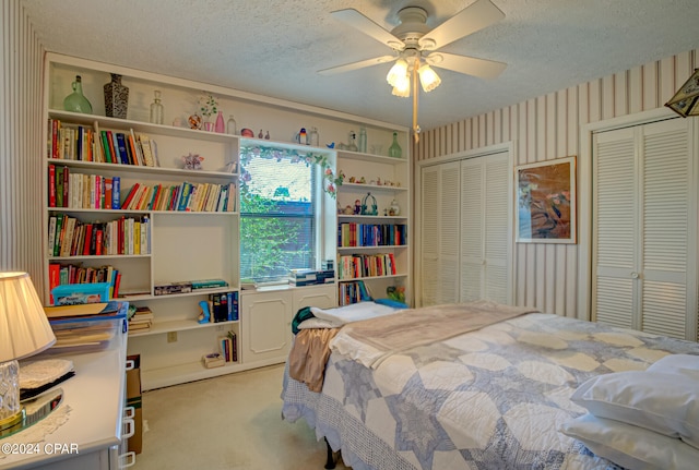 carpeted bedroom featuring ceiling fan and a textured ceiling