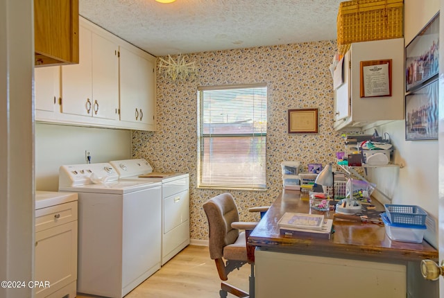 laundry area featuring cabinets, washing machine and dryer, a textured ceiling, and light hardwood / wood-style flooring