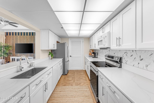 kitchen with white cabinets, sink, ceiling fan, appliances with stainless steel finishes, and light parquet flooring