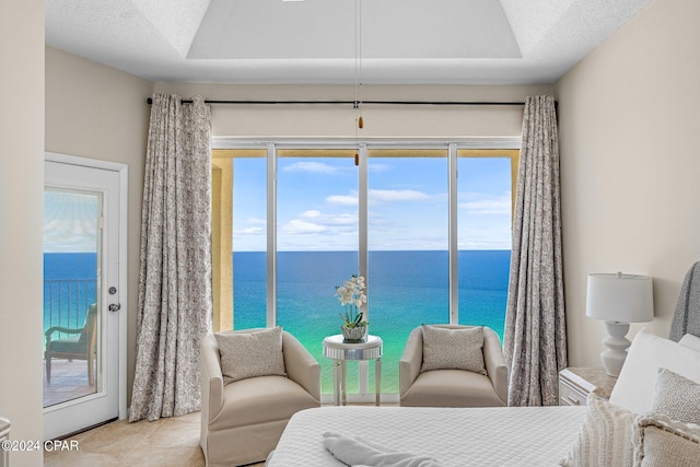 living area with a water view, light tile patterned floors, and a textured ceiling