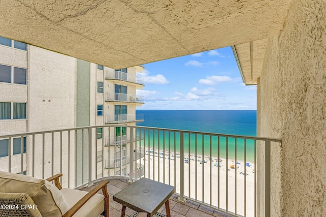 balcony with a water view and a view of the beach