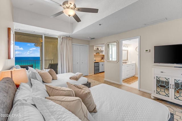 tiled bedroom featuring ensuite bathroom, a water view, ceiling fan, access to exterior, and a textured ceiling