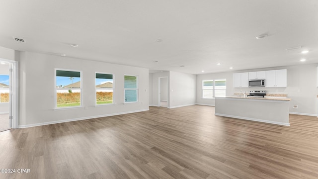 unfurnished living room featuring plenty of natural light and light wood-type flooring