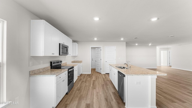 kitchen with a center island with sink, white cabinets, sink, light hardwood / wood-style flooring, and appliances with stainless steel finishes