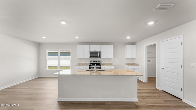 kitchen featuring white cabinets, stainless steel appliances, and a kitchen island with sink