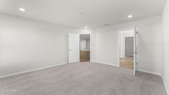 unfurnished bedroom featuring light colored carpet, a spacious closet, and a closet