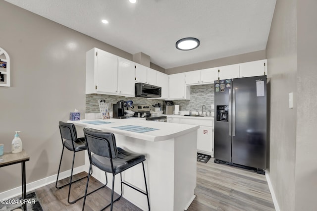 kitchen with appliances with stainless steel finishes, a breakfast bar, kitchen peninsula, and white cabinets