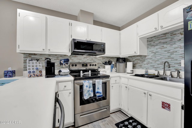 kitchen featuring appliances with stainless steel finishes, decorative backsplash, white cabinetry, and sink