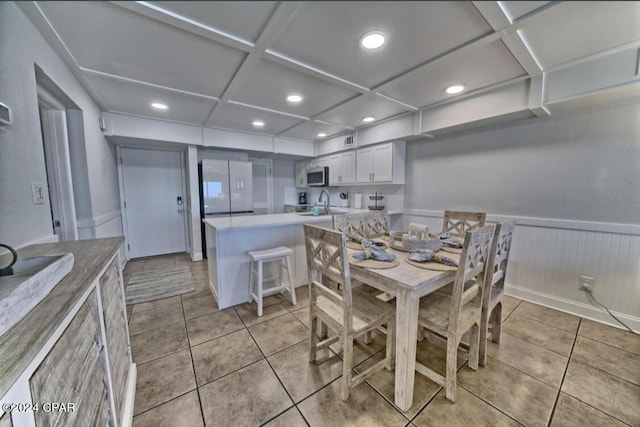 tiled dining area with sink and coffered ceiling