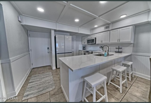 kitchen with kitchen peninsula, stainless steel appliances, white cabinetry, and a breakfast bar area