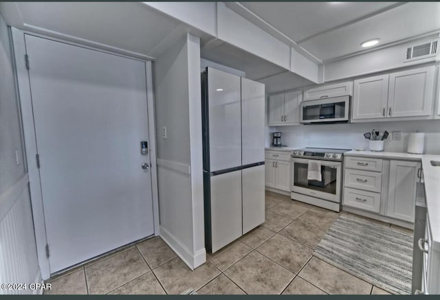 kitchen featuring white cabinets, light tile patterned flooring, and appliances with stainless steel finishes