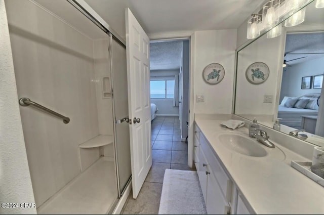 bathroom featuring tile patterned flooring, ceiling fan, a shower with shower door, and vanity