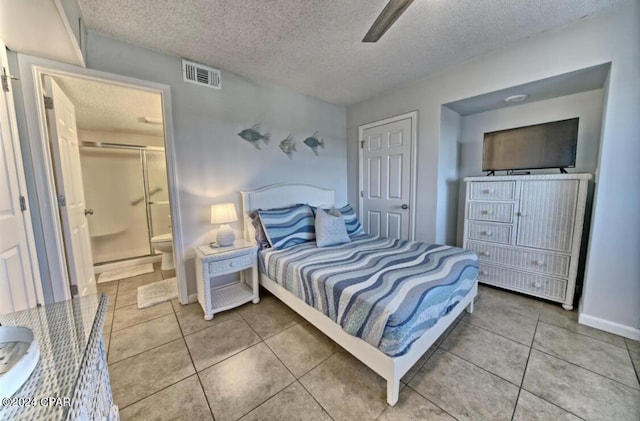 tiled bedroom featuring ceiling fan, a textured ceiling, connected bathroom, and a closet