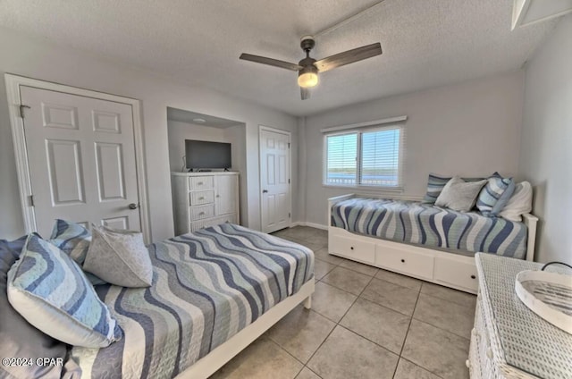 bedroom with ceiling fan, light tile patterned floors, and a textured ceiling