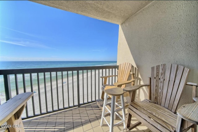 balcony with a water view and a view of the beach