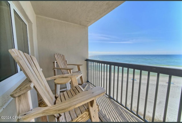 balcony featuring a water view and a beach view