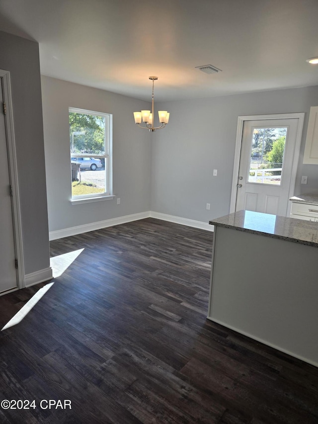 unfurnished dining area featuring dark wood-type flooring and a notable chandelier