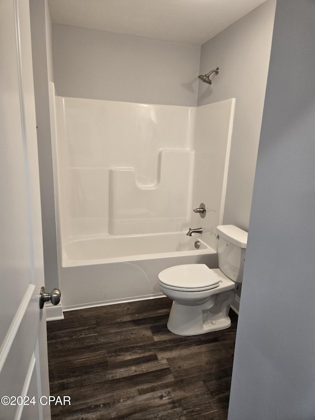 bathroom featuring hardwood / wood-style flooring, shower / washtub combination, and toilet