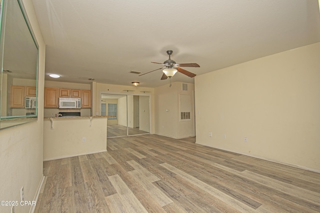 unfurnished living room featuring light wood-style floors, ceiling fan, and visible vents