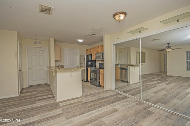 kitchen with stainless steel appliances, open floor plan, visible vents, and a peninsula