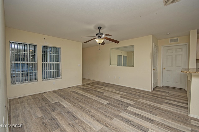spare room featuring light wood finished floors, visible vents, and a ceiling fan