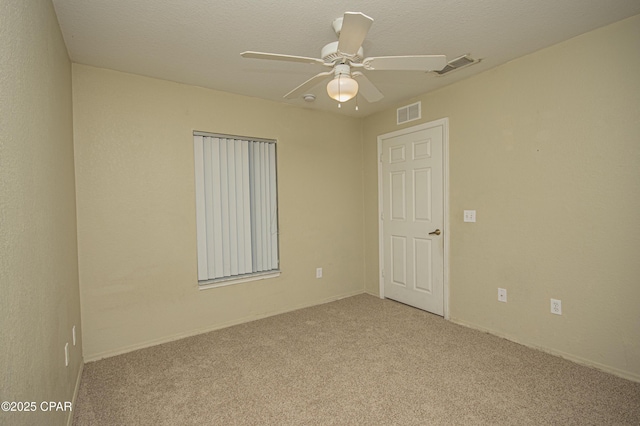 carpeted spare room with a textured ceiling, a ceiling fan, and visible vents