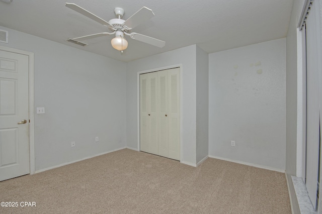 unfurnished bedroom featuring ceiling fan, a closet, visible vents, carpet flooring, and baseboards