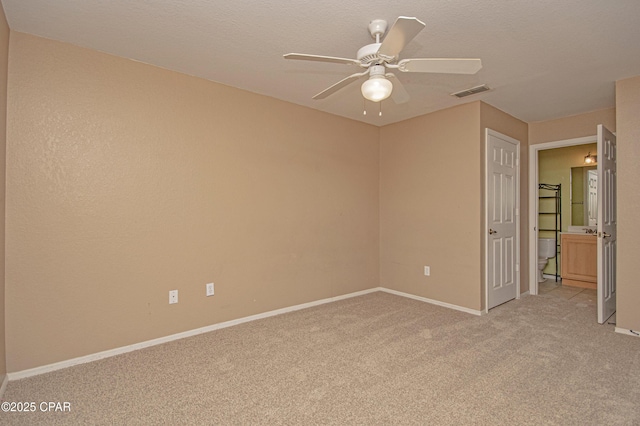 interior space featuring baseboards, light carpet, a textured ceiling, a ceiling fan, and visible vents