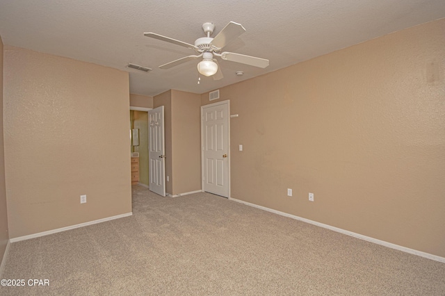 carpeted spare room with a textured ceiling, ceiling fan, baseboards, and visible vents
