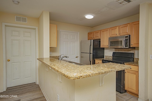 kitchen with visible vents, a sink, freestanding refrigerator, black electric range oven, and stainless steel microwave