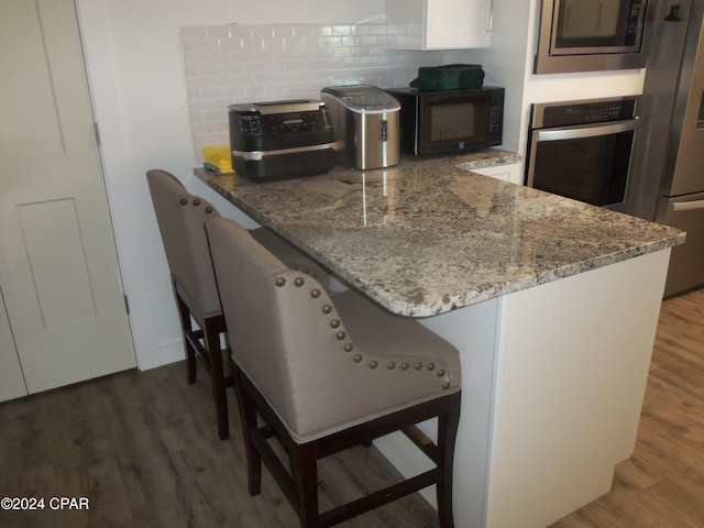 kitchen featuring light stone counters, white cabinetry, stainless steel appliances, and dark hardwood / wood-style floors