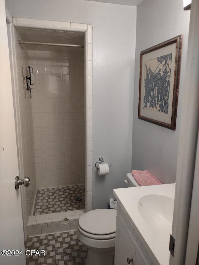 bathroom featuring tile patterned flooring, toilet, vanity, and tiled shower