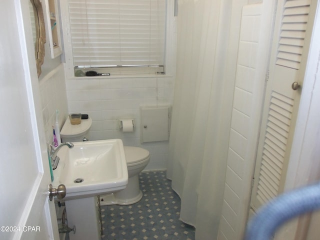 bathroom featuring tile patterned floors, sink, tile walls, and toilet