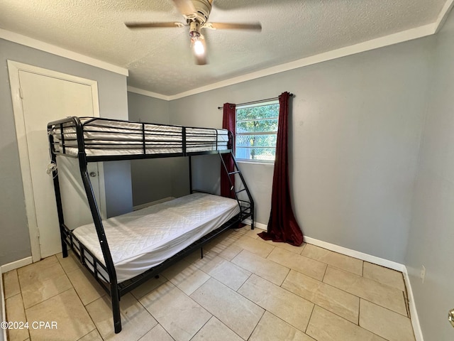 tiled bedroom with ceiling fan, a textured ceiling, and ornamental molding