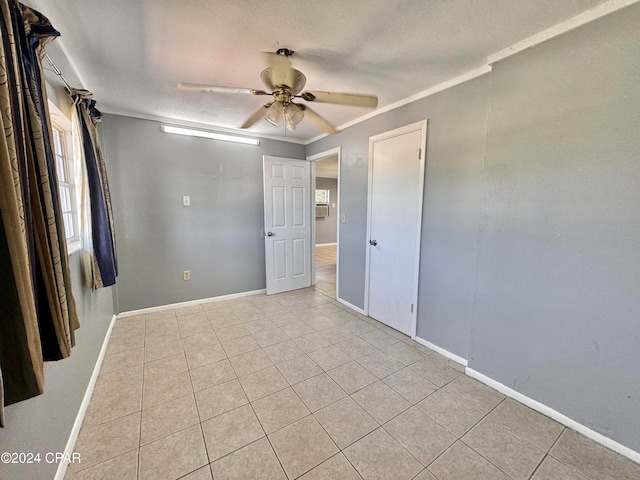 unfurnished room with ceiling fan, crown molding, a textured ceiling, and light tile patterned floors