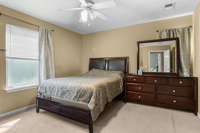 bedroom with ceiling fan, light carpet, and a textured ceiling