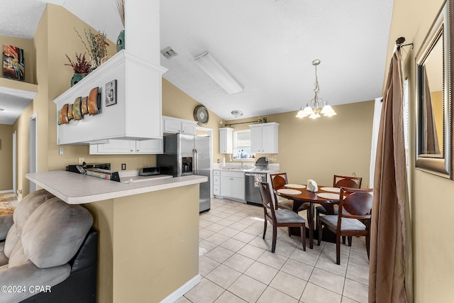 kitchen with kitchen peninsula, appliances with stainless steel finishes, a breakfast bar, white cabinets, and lofted ceiling