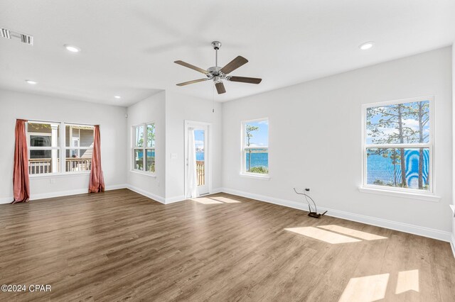 unfurnished living room featuring ceiling fan, wood-type flooring, and a wealth of natural light