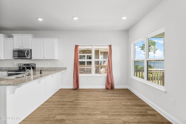 kitchen featuring a breakfast bar, white cabinets, stainless steel appliances, and light hardwood / wood-style floors