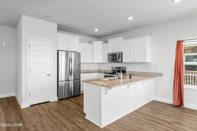 kitchen with appliances with stainless steel finishes, kitchen peninsula, dark hardwood / wood-style floors, and white cabinets