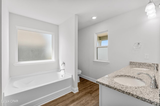 bathroom with vanity, toilet, a tub to relax in, and hardwood / wood-style floors