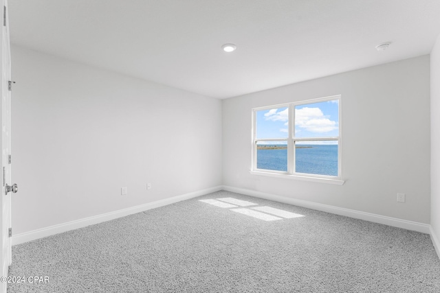 spare room featuring a water view and carpet floors