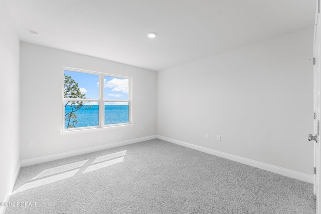 carpeted empty room featuring a water view