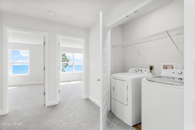 washroom with carpet, a healthy amount of sunlight, independent washer and dryer, and a water view