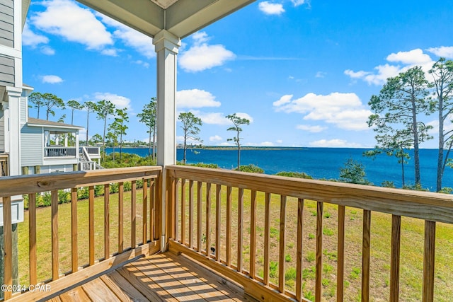 deck with a water view and a lawn