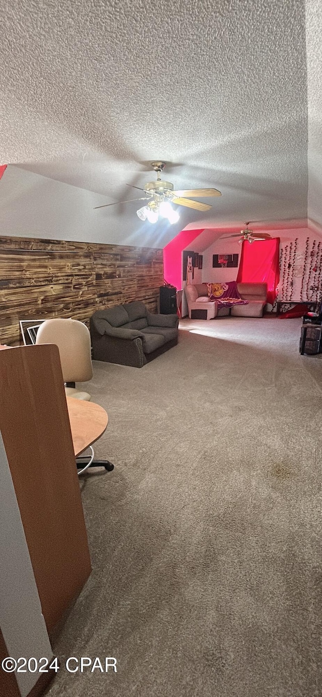 living room with carpet, a textured ceiling, ceiling fan, and wooden walls