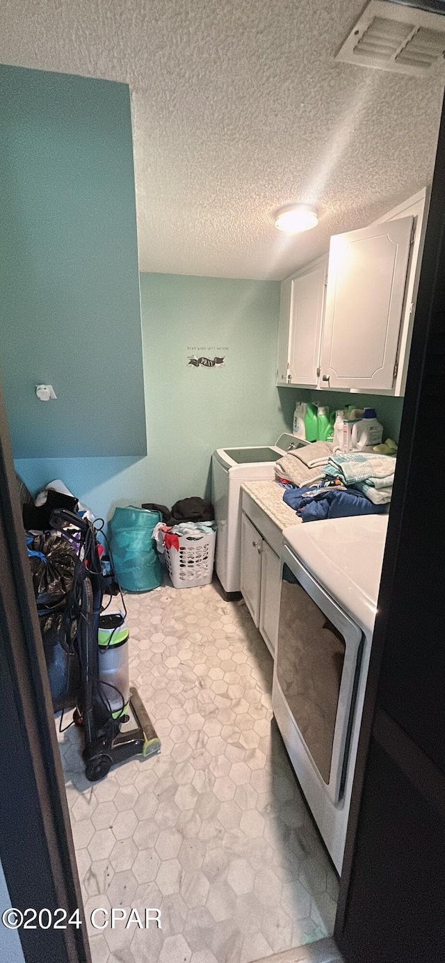 laundry room featuring cabinets and a textured ceiling